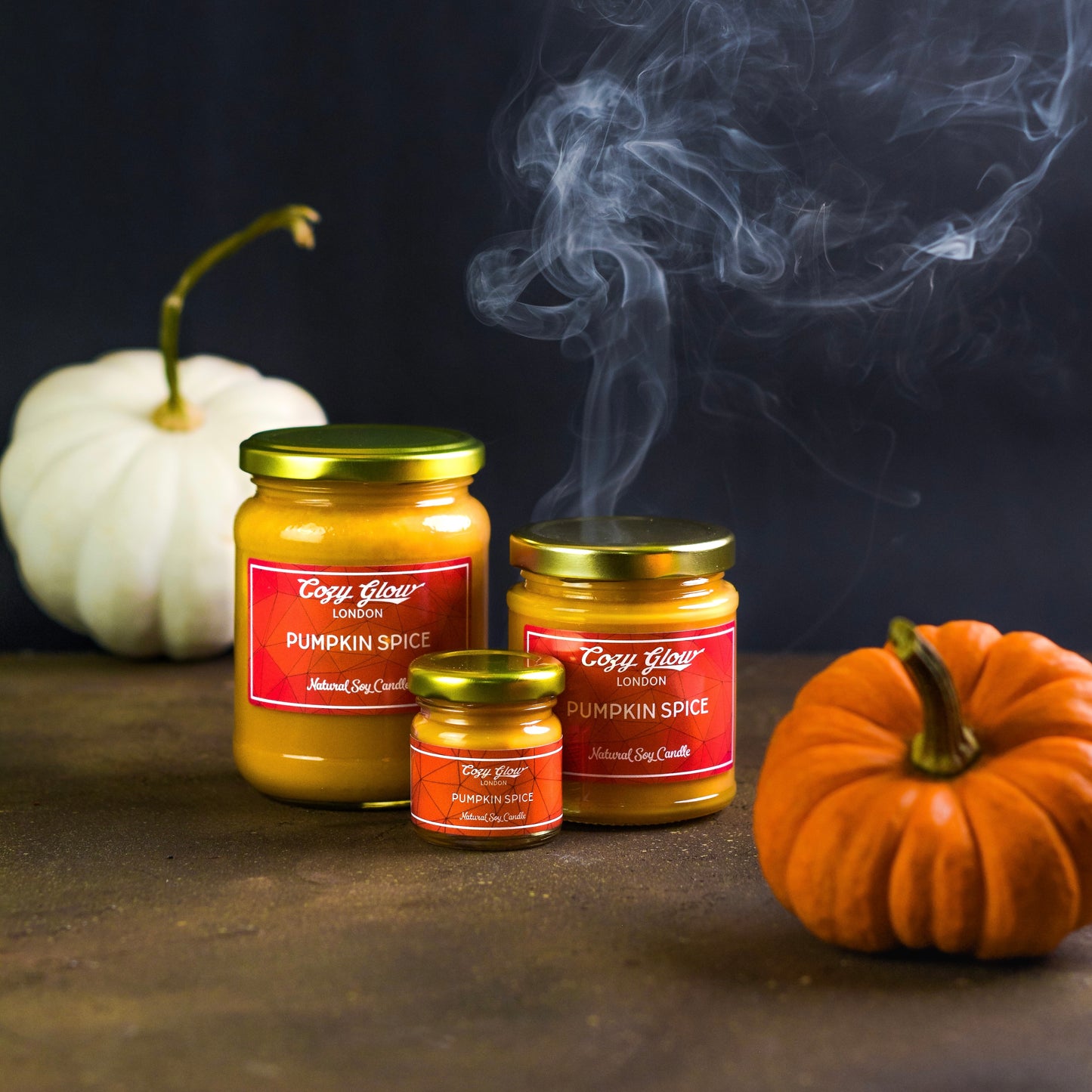 Our three sizes of Pumpkin Spice candled with smoke rising in the background to create an easy spooky feeling